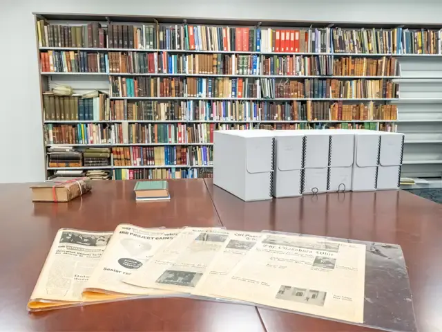 Image of a table with some archive material on top and book shelves with books in the background